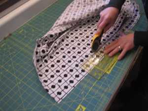 I move my ruler and my blade together down the fabric. I slide the ruler, check to make sure it is lined up so that the black line on the fabric is 1/4" away from the edge of the ruler and then I cut. I do this all the way down the fabric edge.